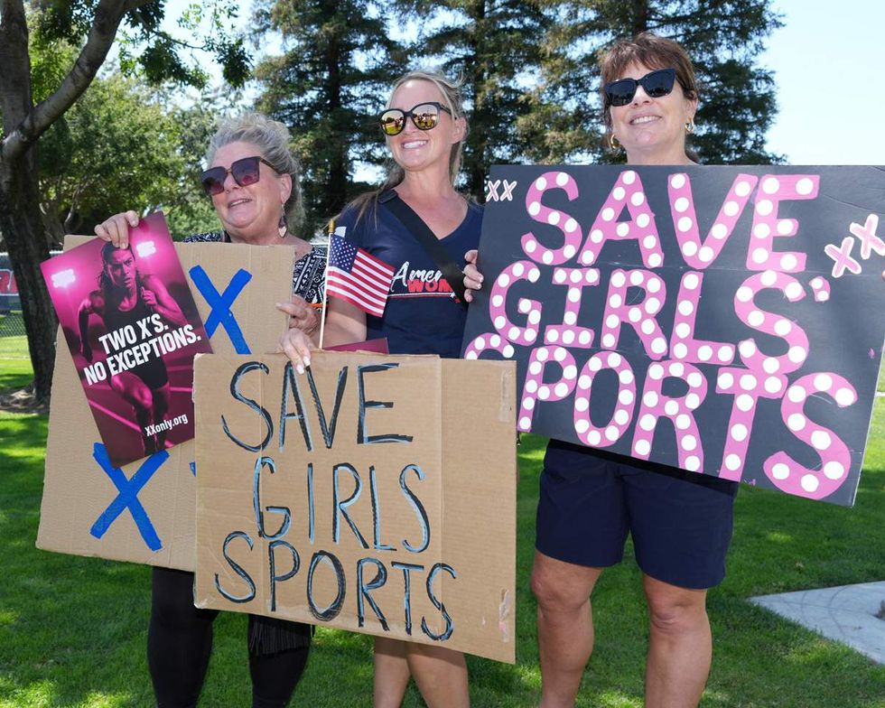 People holding protest signs that read save girls sports