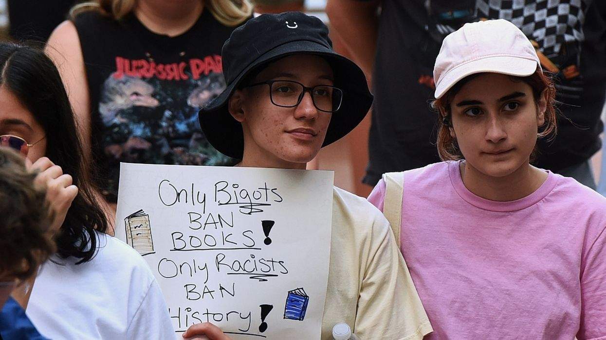 people protesting holding a sign that says only bigots ban books, only racists ban history
