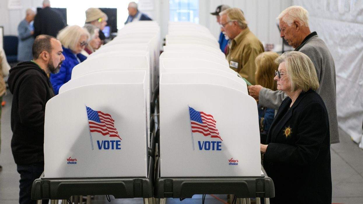 people voting in a line of stations at a polling place