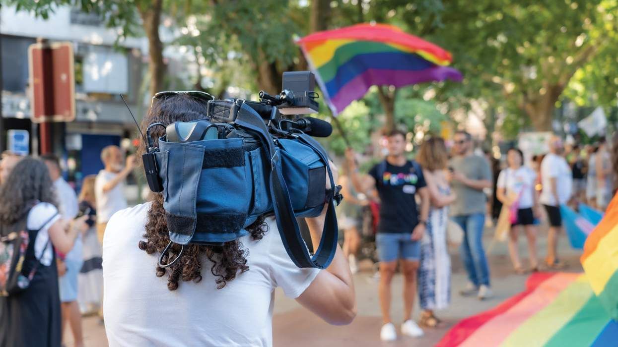 person holding a video camera filming a live lgbtq pride event