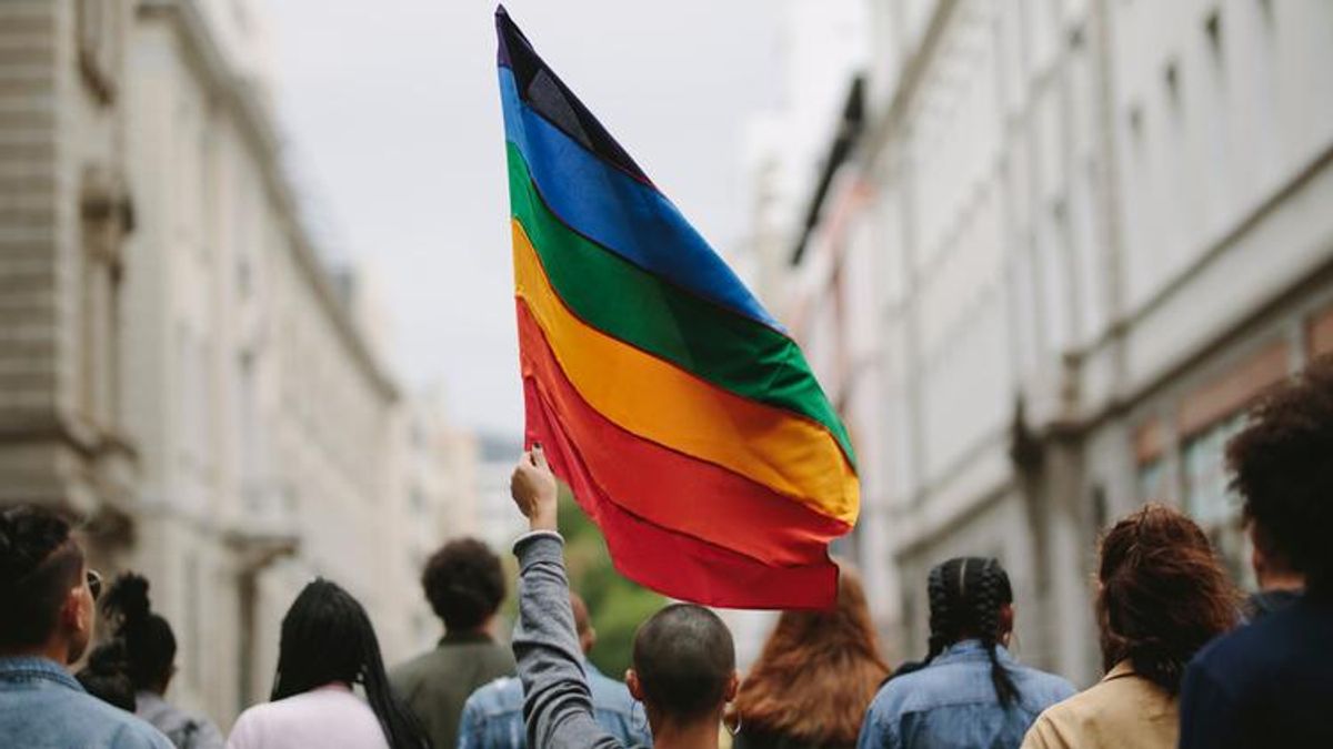 Person holding rainbow flag with others around them