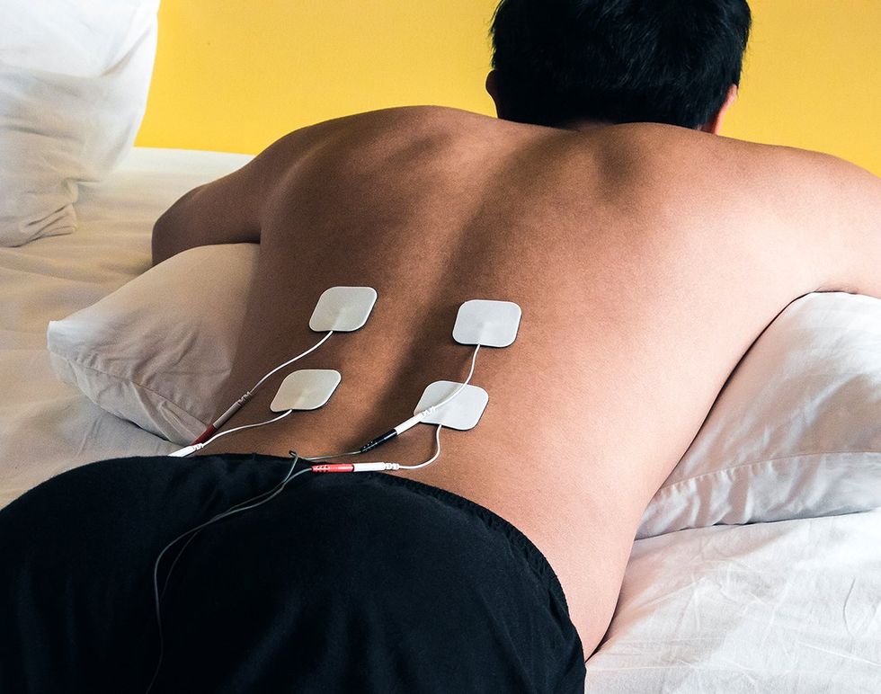 person laying down with tens unit electrical pads on their lower back