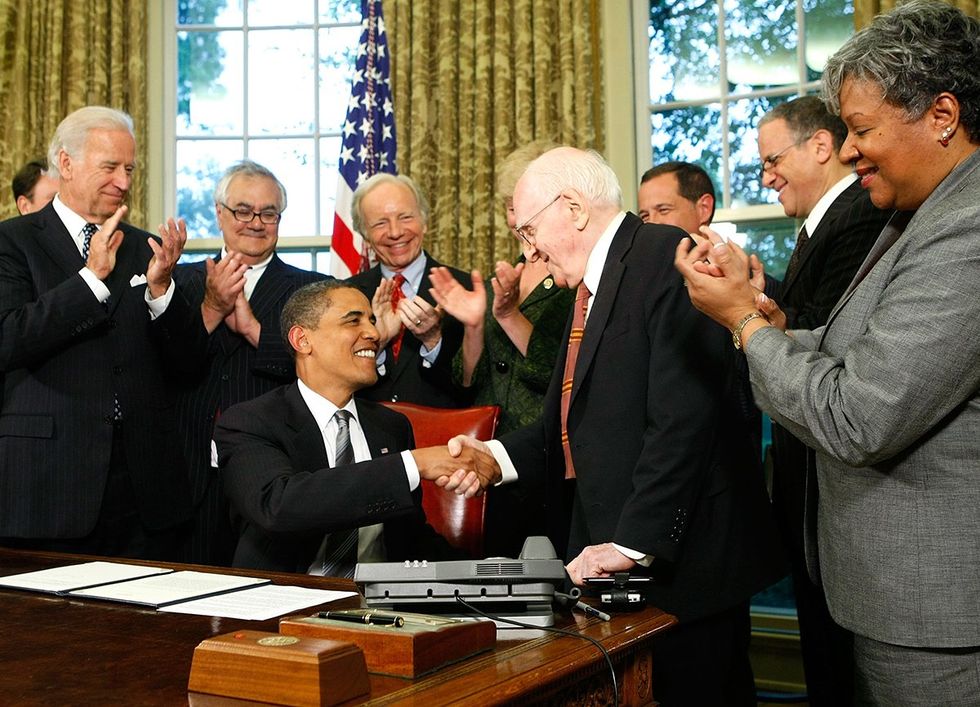 President Barack Obama shakes hands with gay rights activist Frank Kameny surrounded by others in the white house June 2009