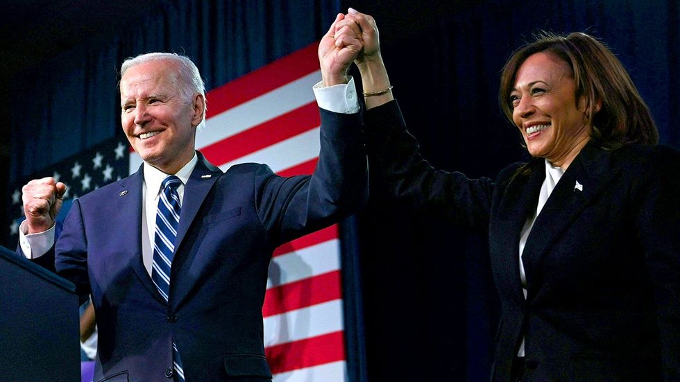 President Joe Biden and Vice President Kamala Harris hold hands, cheer