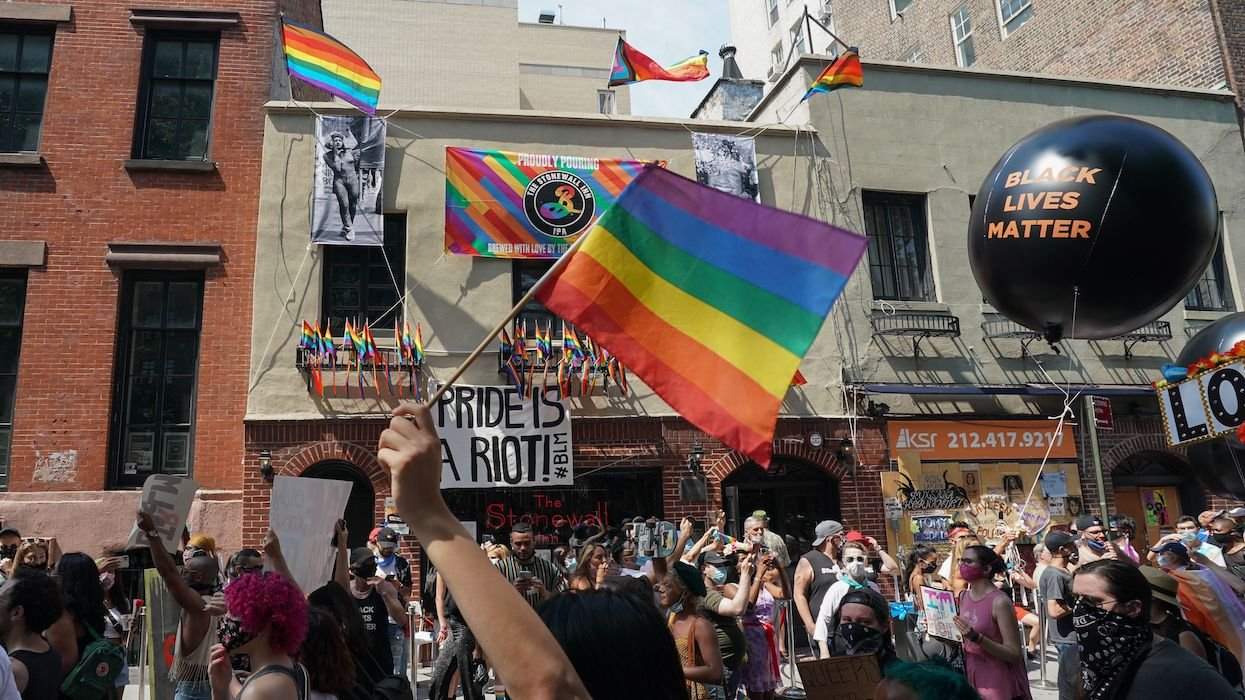 Protest in front of Stonewall Inn with rainbow flags and Black Lives Matter signs
