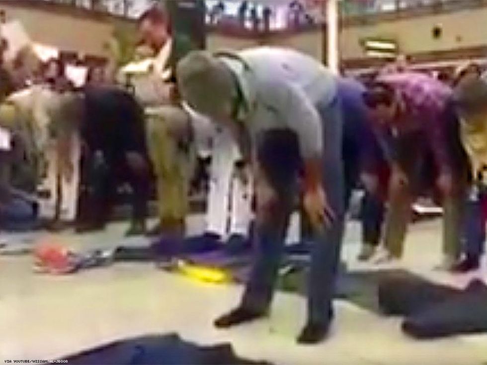 Protesters form a circle around men in prayer at Denver International Airport