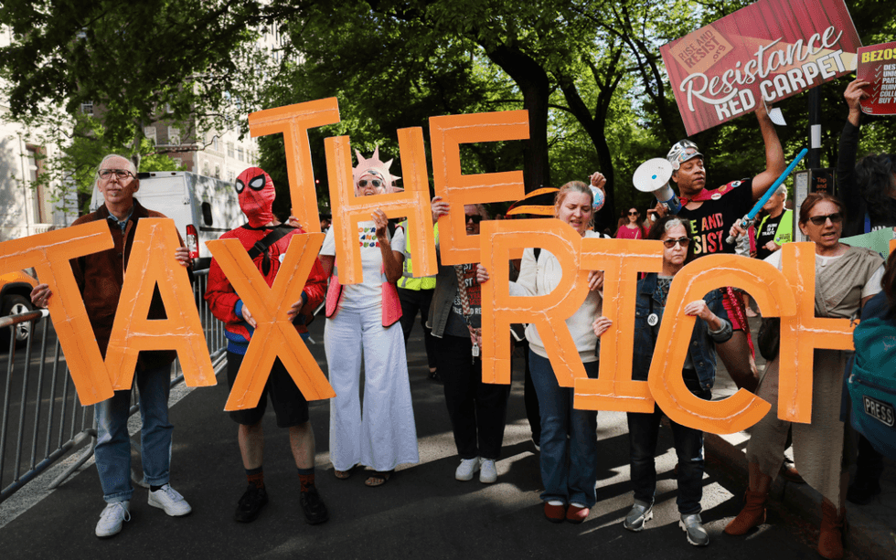 Protesters gather blocks away from where the Met Gala is being held in Manhattan on May 04, 2026 in New York City, holding letters signs that spell TAX THE RICH.