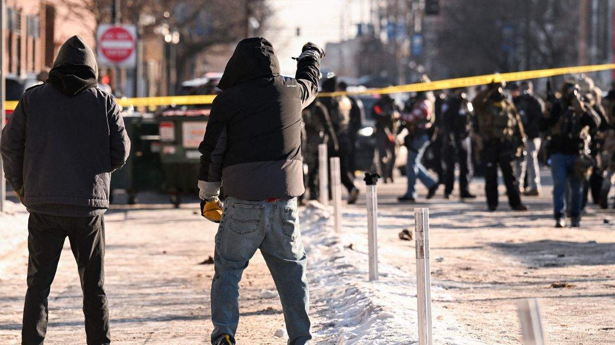 Protesters gesture toward federal agents as demonstators gather near the site where a man was shot by federal agents in Minneapolis Saturday morning.