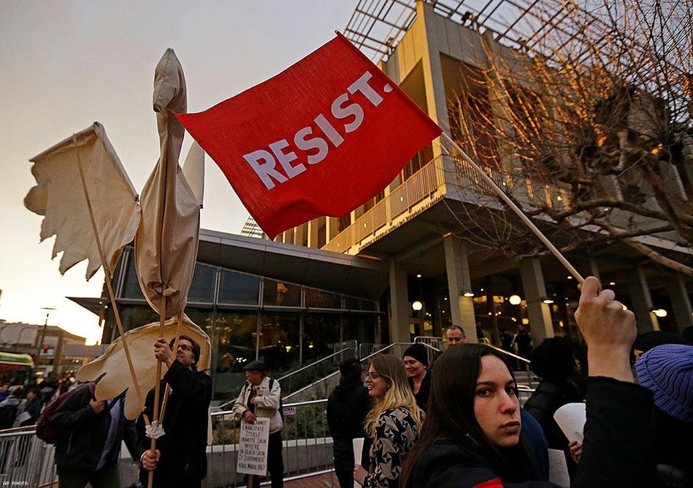Protesters holding up a "resist" banner.