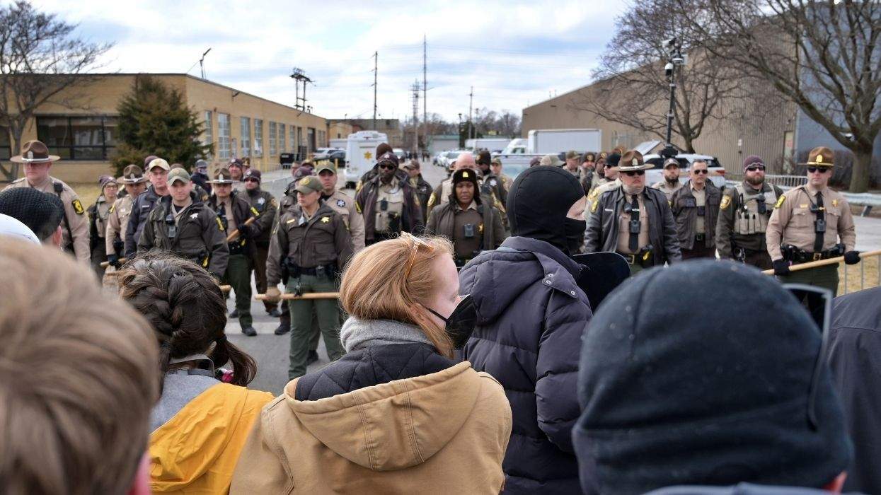 protesters stand across police officers with clubs
