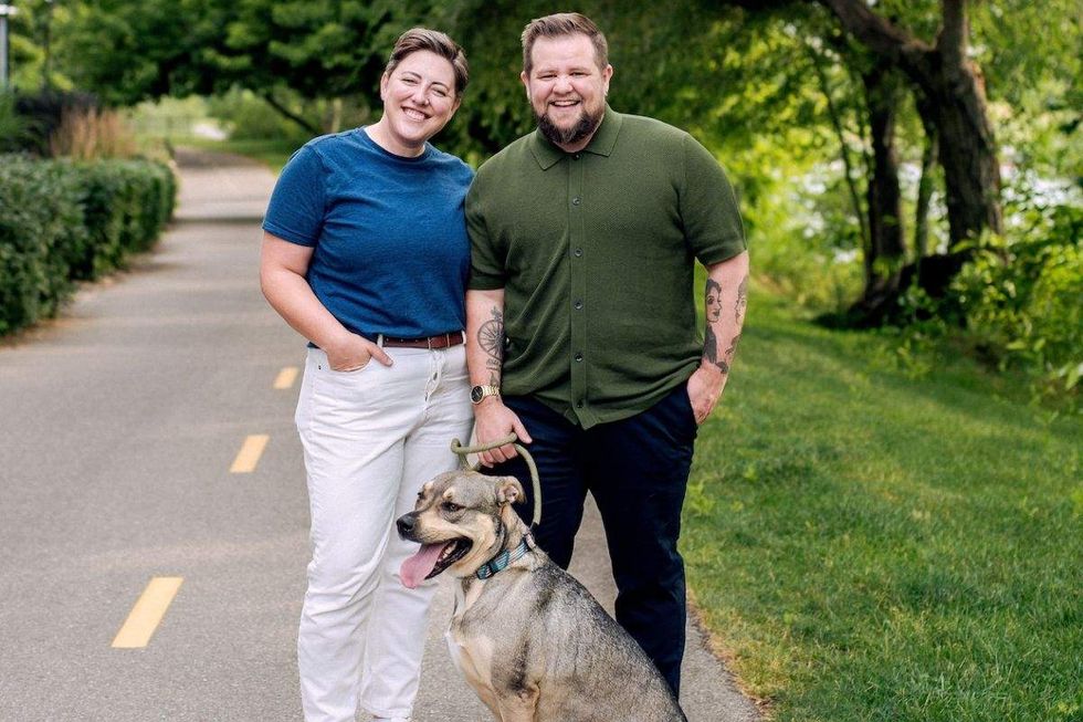 reilly o'connor wearing white pants and a blue shirt and partner nikson mathews wearing a green shirt and black pants with an adult dog