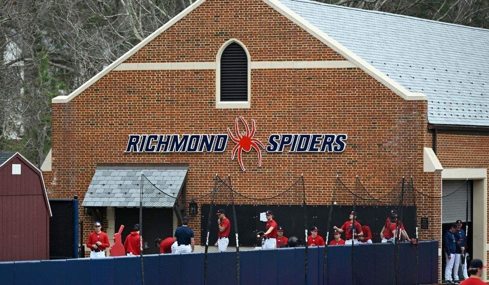 richmond spiders logo on the side of a building with baseball players standing below it