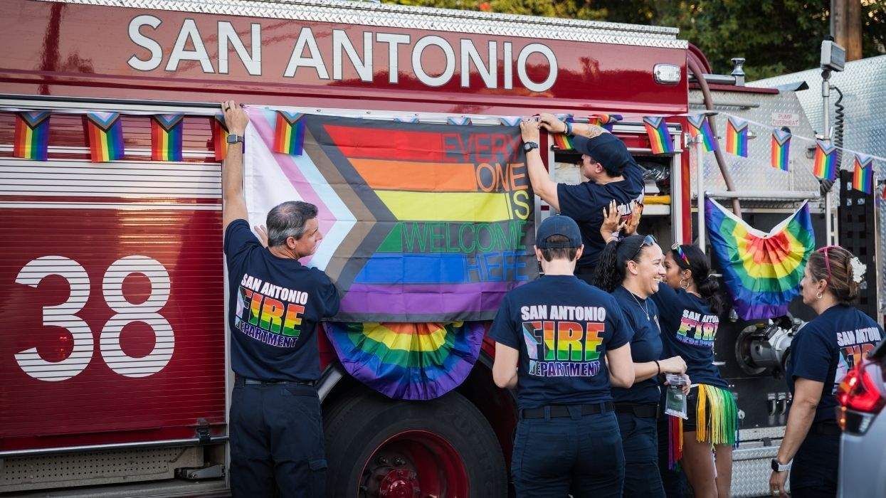 san antonio firefighters with pride flag on he fire ruck