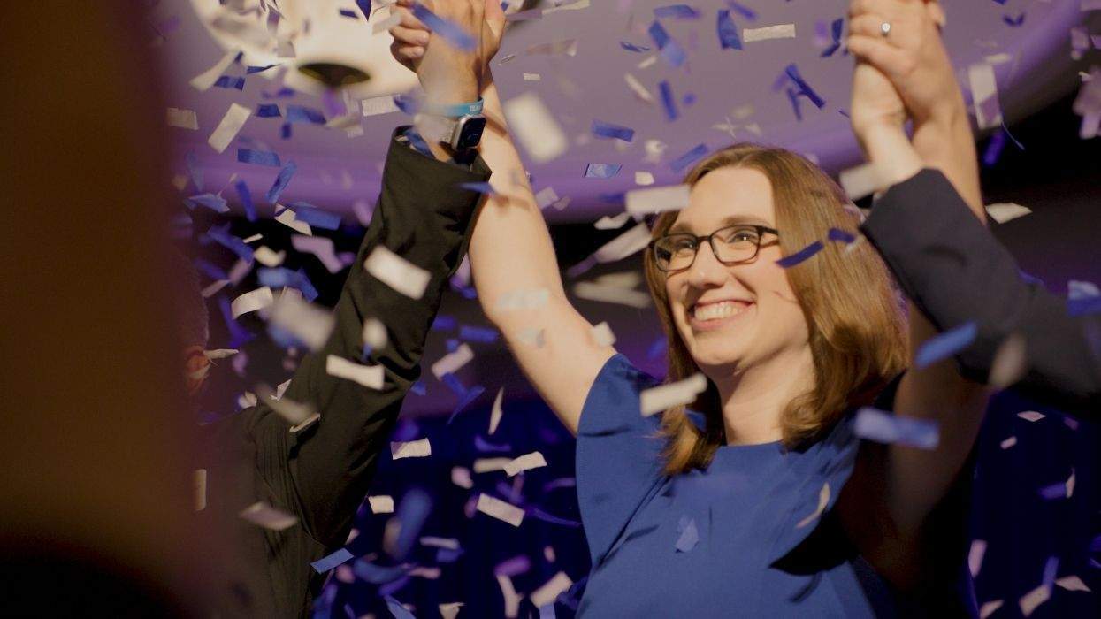 Sarah McBride with confetti and arms raised in victory