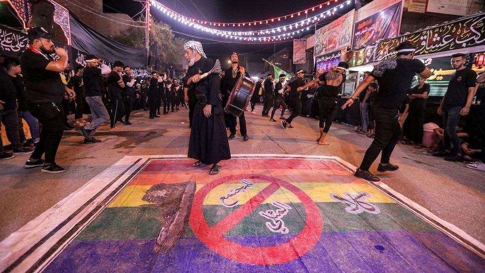 Shiite Muslim devotees self-flagellate over an unfurled banner on the ground depicting the Pride rainbow flag defaced with a boot and the Arabic slogan "no to homosexual society," in Iraq's southern city of Nasiriyah on July 25.