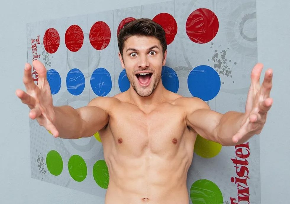 shirtless man in front of twister game on the wall