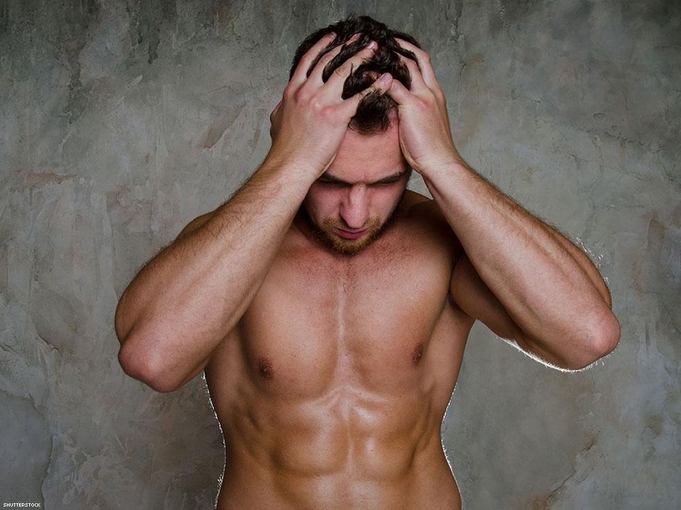 shirtless man with hands on head looking down