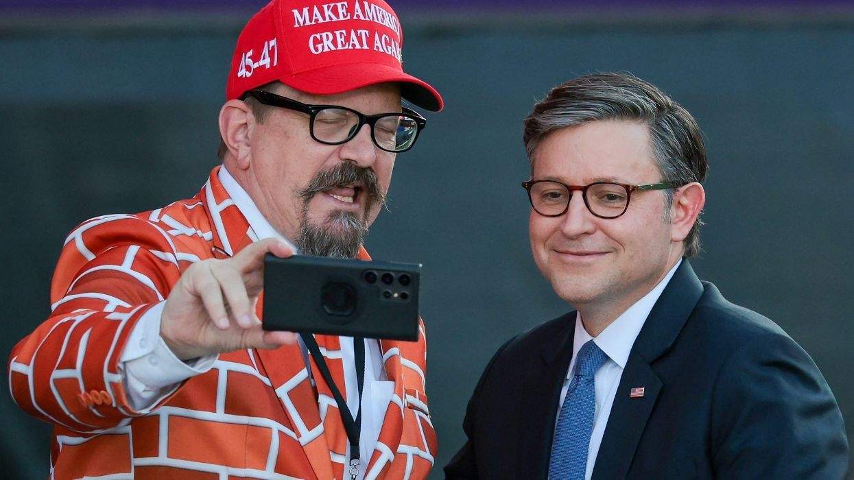 speaker mike johnson posing for a photo with somebody wearing a maga hat and dressed as a wall