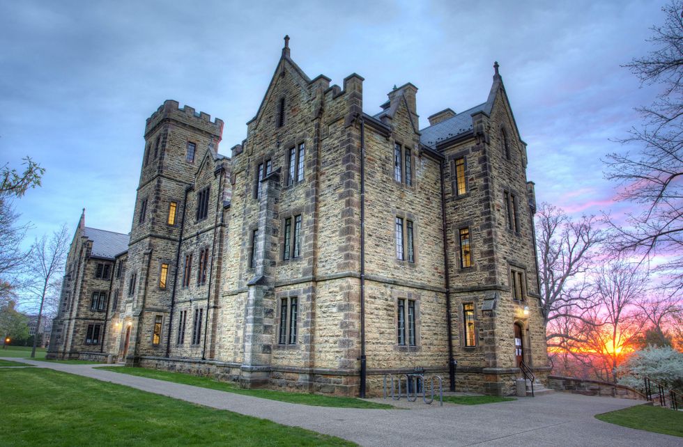 Sun sets over a historic-looking stone building at Kenyon College.