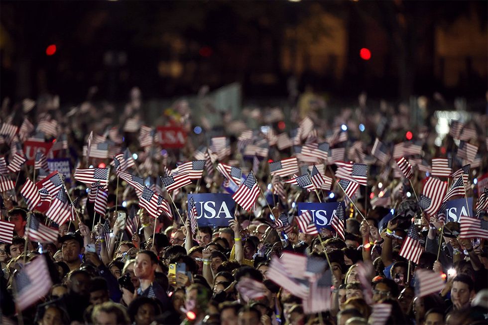 Supporters hold American flags as Democratic presidential nominee U.S. Vice President Kamala Harris speaks during a campaign rally on the Ellipse