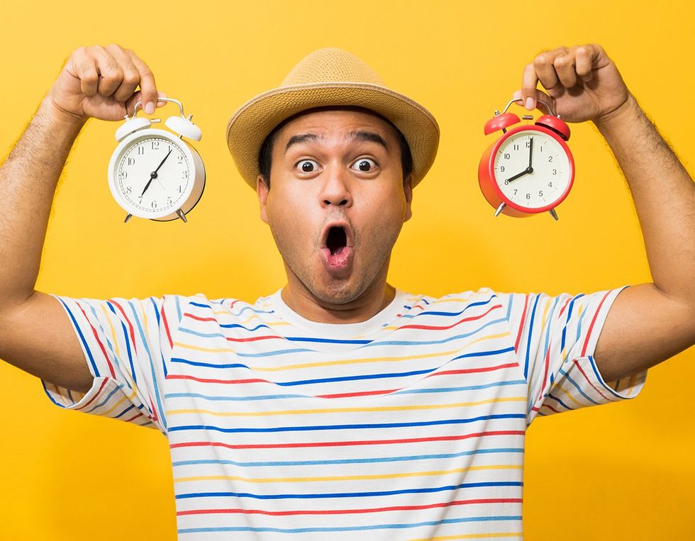 surprised guy holding two alarm clocks