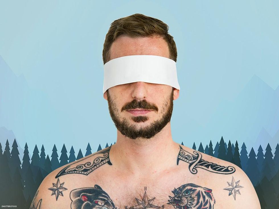tattooed man with blindfold over illustrated trees and sky background