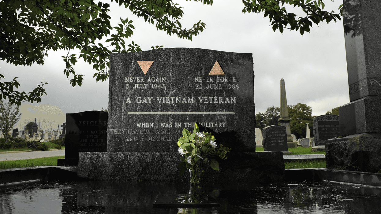 The grave marker of gay Vietnam veteran Leonard Matlovich sits in a cemetery on a rainy day, with flowers placed at the base of the headstone