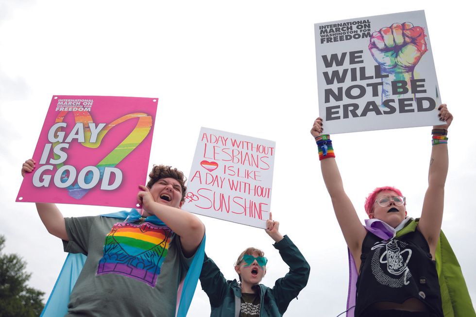 three people holding signs and cheering at worldpride