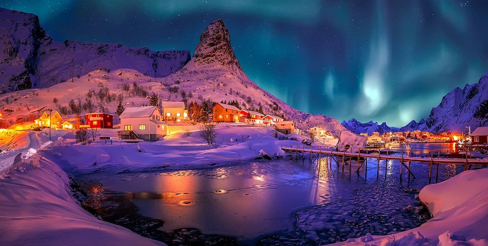 Top 15 safest countries for LGBTQ+ travelers - Northern lights fill the night skies above the village of Reine in Norway\u2019s Lofoten Islands