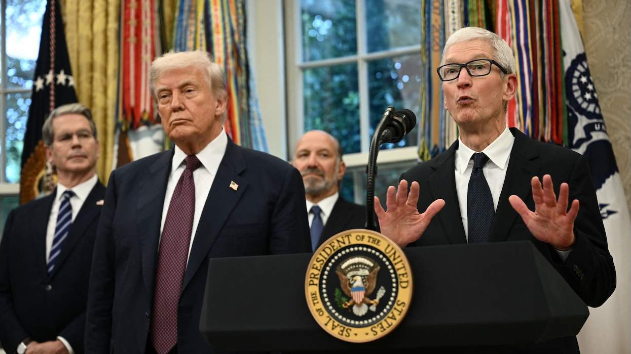 Trump and Tim Cook standing next to each other. Cook is mid-sentence with his hands up. Trump looks straight ahead.