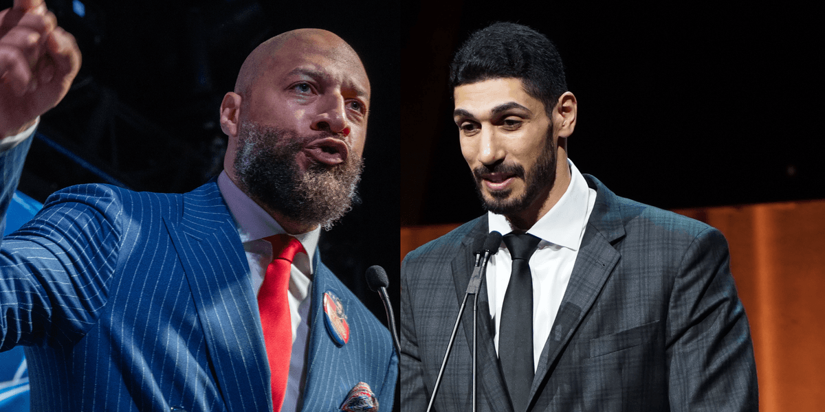 Two men in suits speaking at microphones on stage accompanying Advocate coverage of the WNBA eligibility dispute.