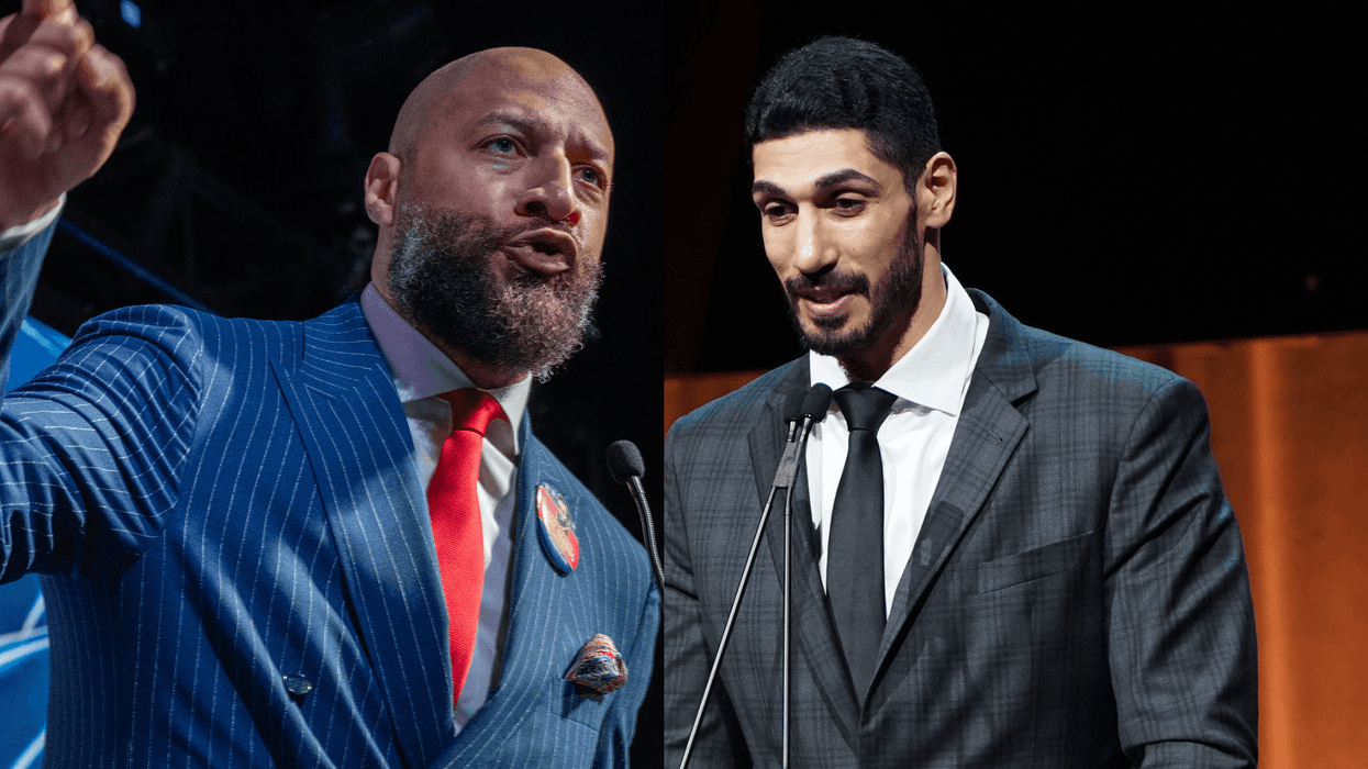 Two men in suits speaking at microphones on stage.