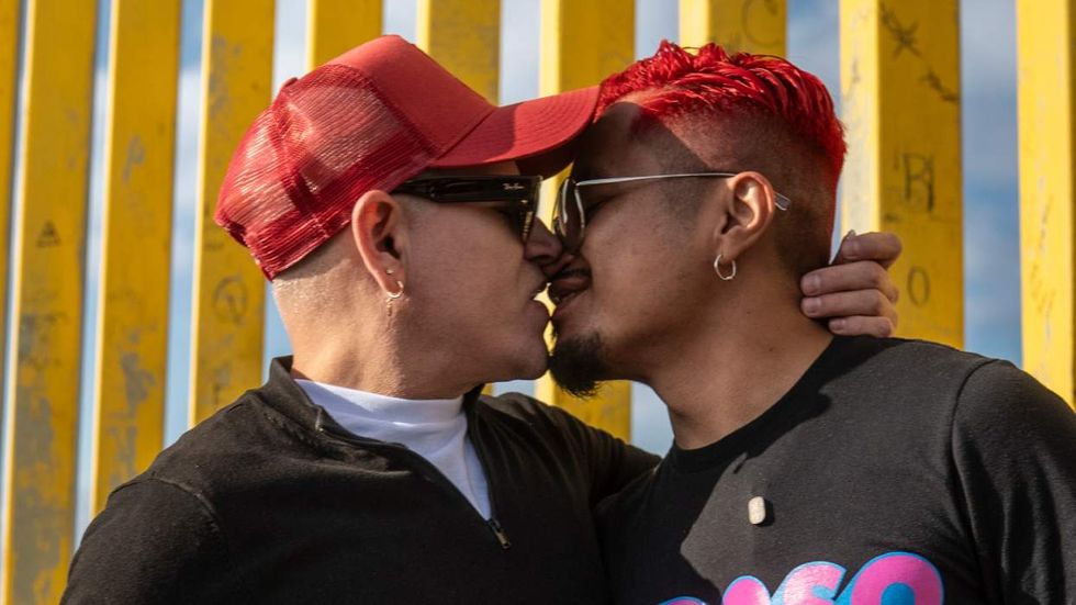 Two men kiss in front of U.S.-Mexico border