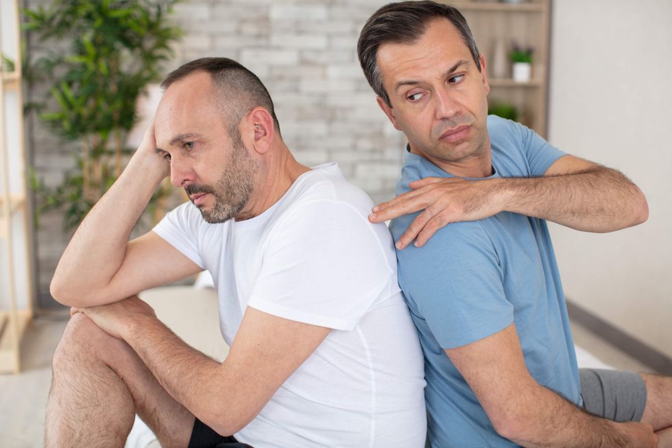 two men sitting back to back