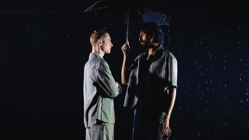 Two people standing under an umbrella