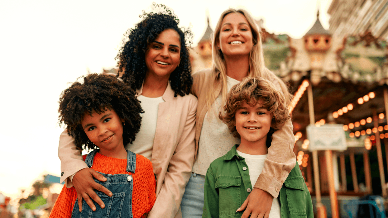 Two women pose with two smiling children outdoors.