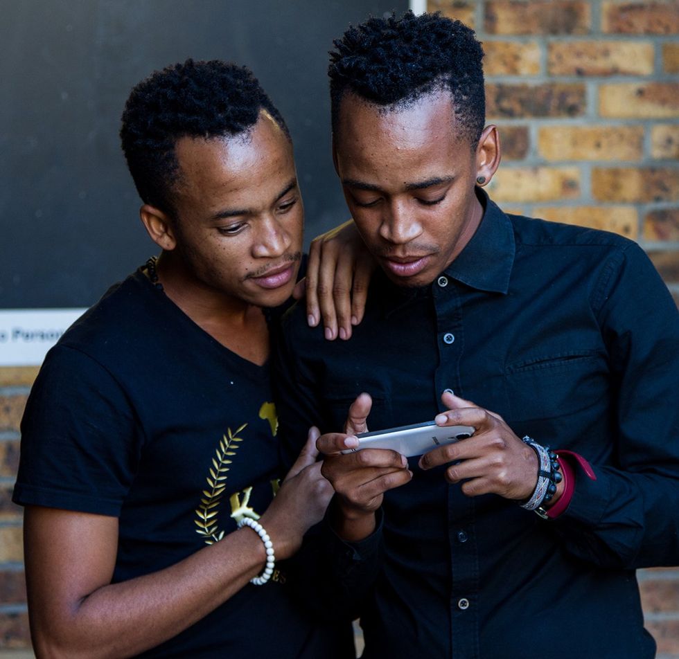 two young black men looking at a cellphone together in Cape Town South Africa bar