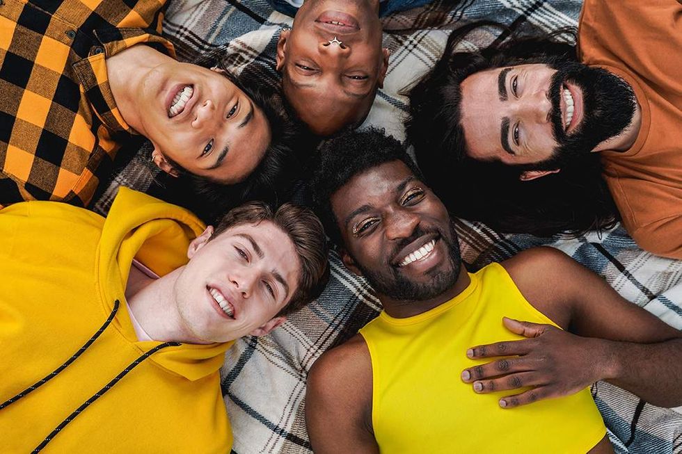 \u200bA group of queer men lying with their heads together on a blanket.