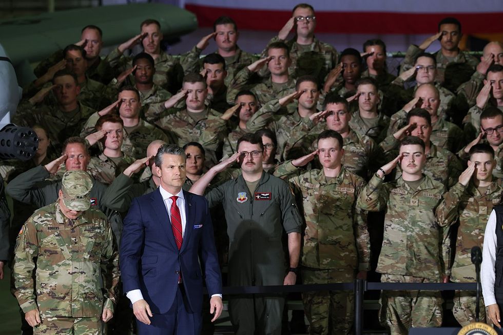 \u200bDefense Secretary Pete Hegseth surrounded by soldiers in various phases of salute
