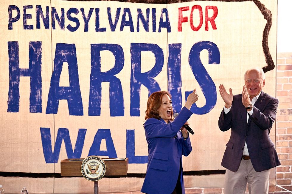 US Vice President and Democratic presidential candidate Kamala Harris speaks as her running mate Minnesota Governor Tim Walz cheers during a stop on their campaign bus tour in Rochester Pennsylvania
