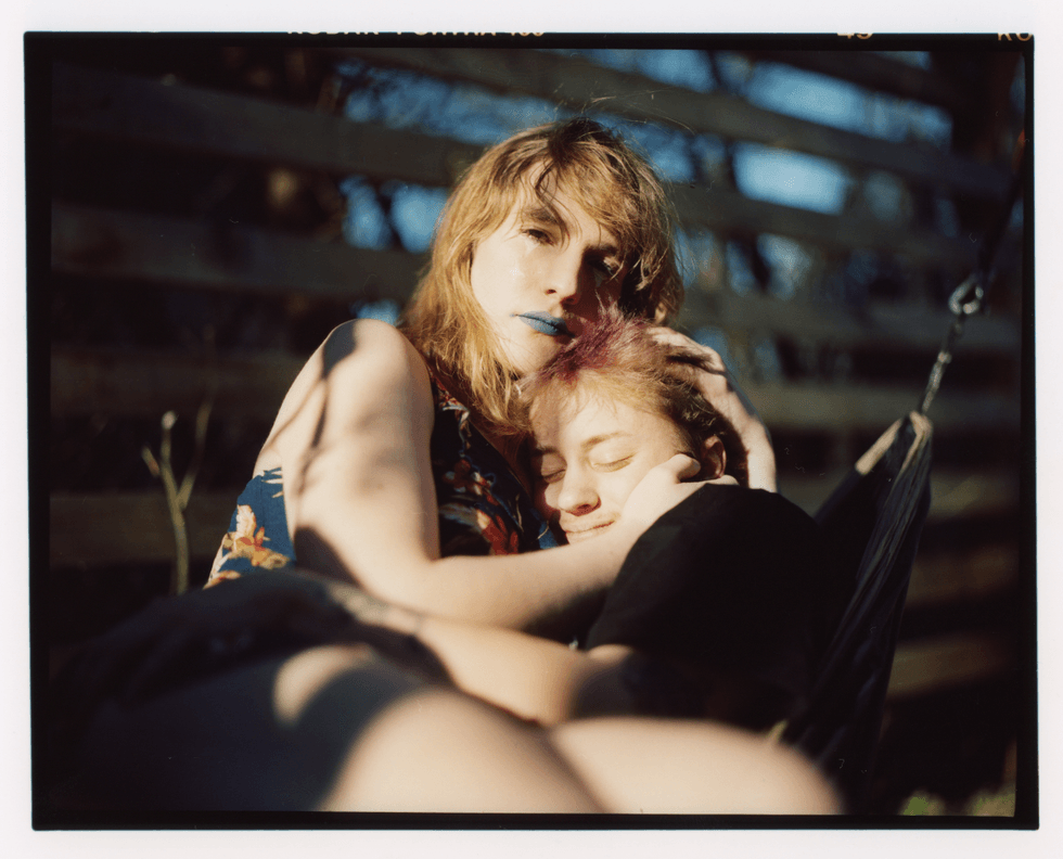 Vali & Mad sit closely together in a hammock outdoors.