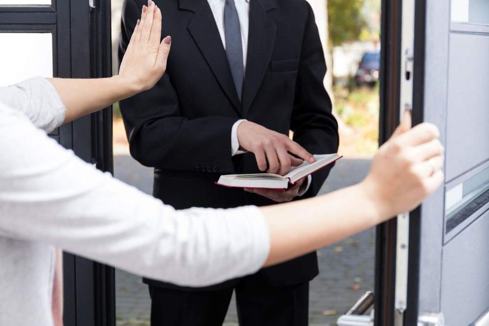 Woman annoyed with religious doorknocker