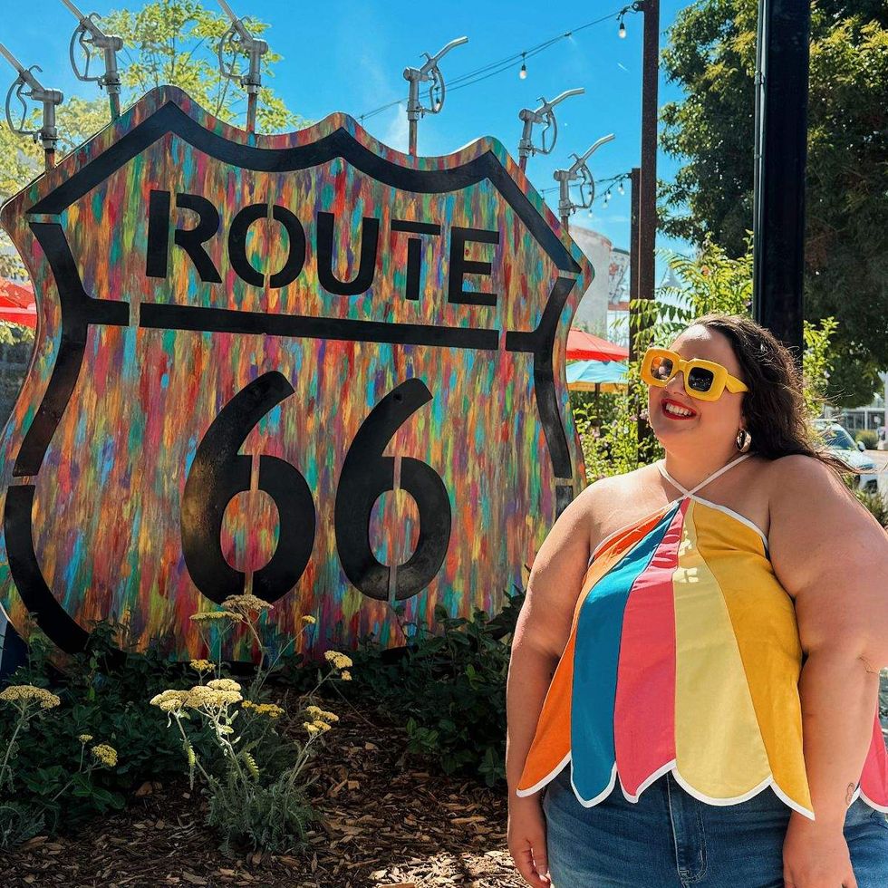 Writer Alysse Dalessandro standing at the Route 66 sign in Albuquerque, New Mexico.