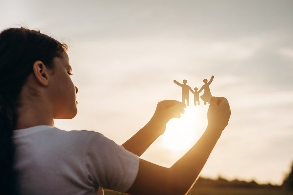 Young girl holding up paper cutout of a family