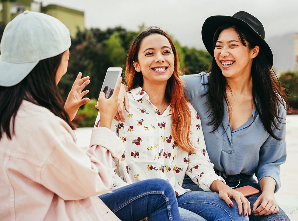 young happy Asian queer transgender throuple taking cellphone pics in South Korea
