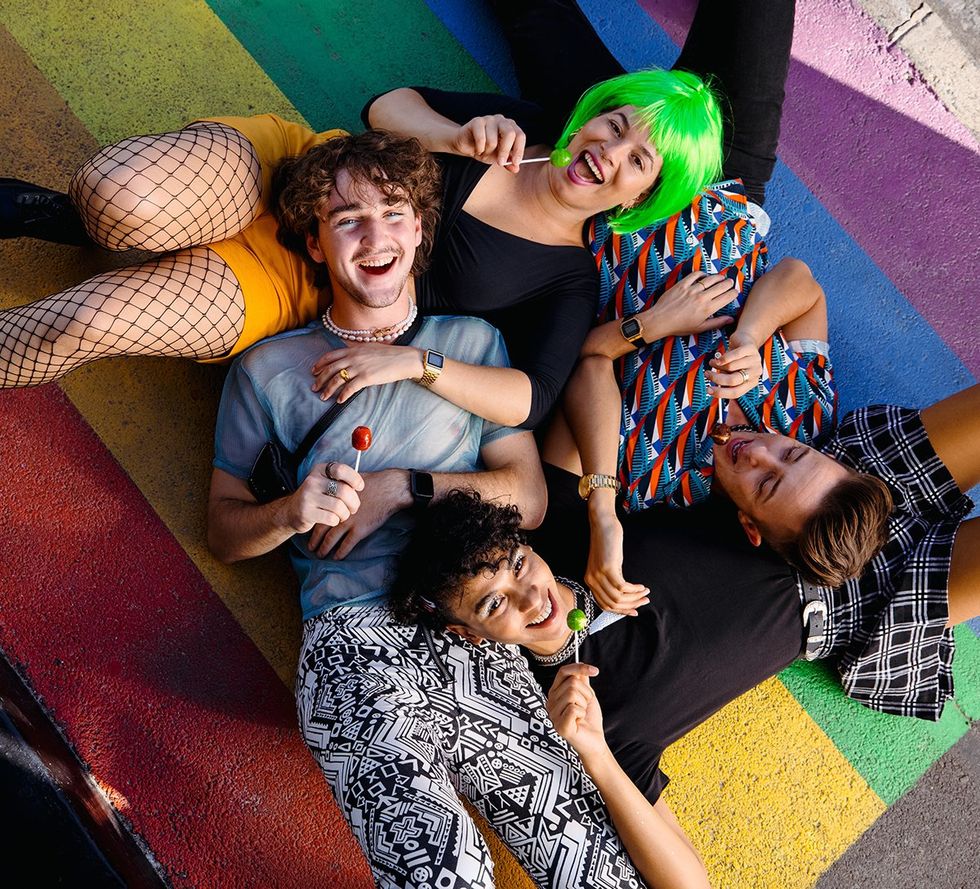 young happy queer friends in LGBTQIA community rainbow crosswalk