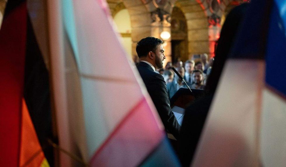 zohran mamdani from behind shot through pride flags