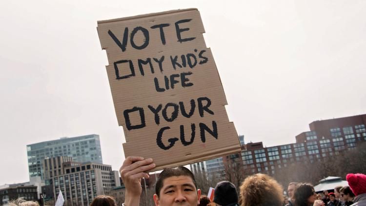 Man holding sign that reads "Vote, My Kids's Life, Your Gun"