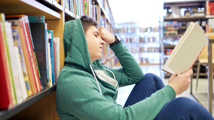 Teenager reading in a library