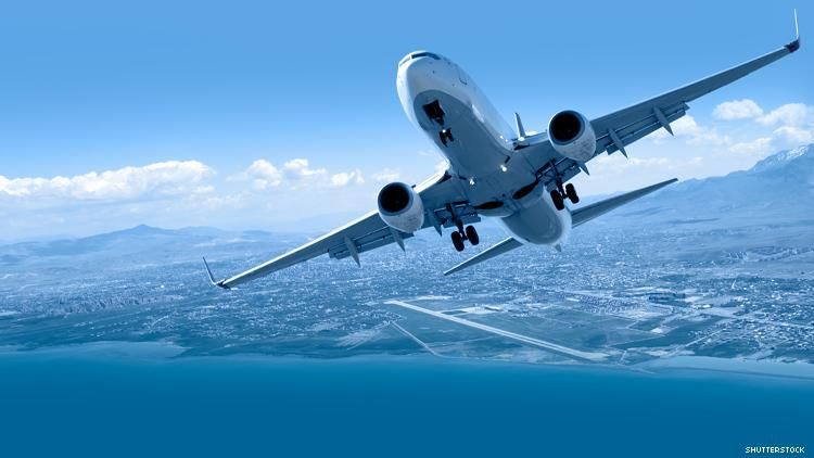 airplane taking off over mountains and ocean